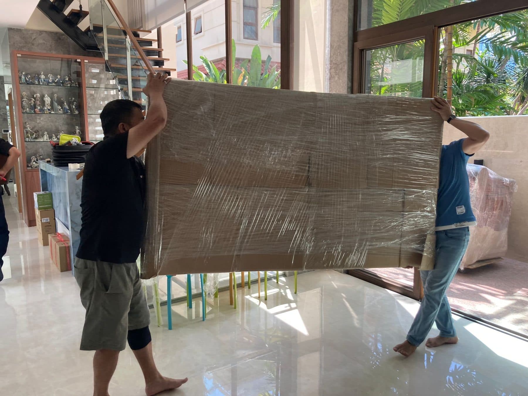 Two movers carrying a wrapped TV