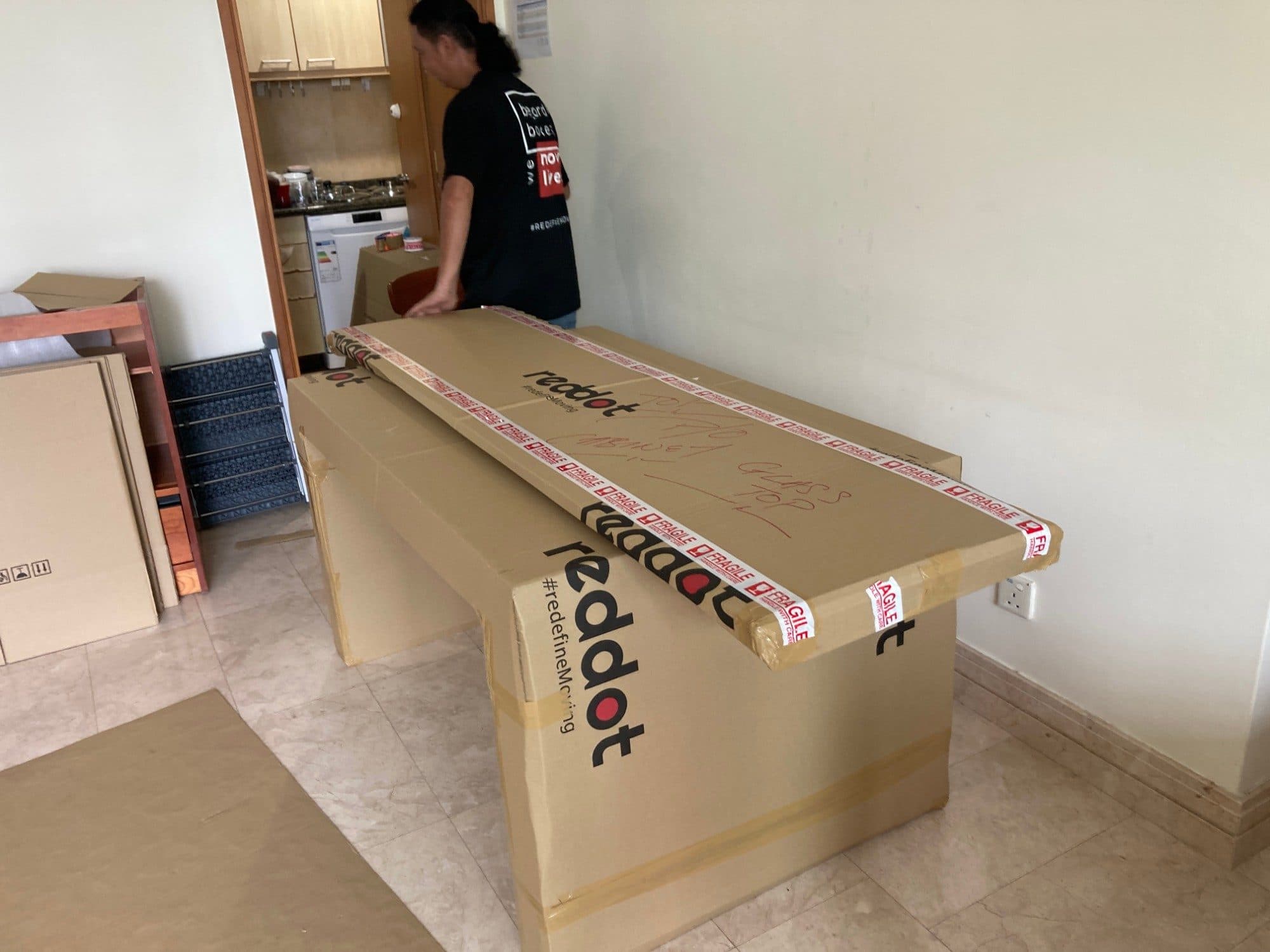 A Reddot packer sealing a glass-top box with fragile tape